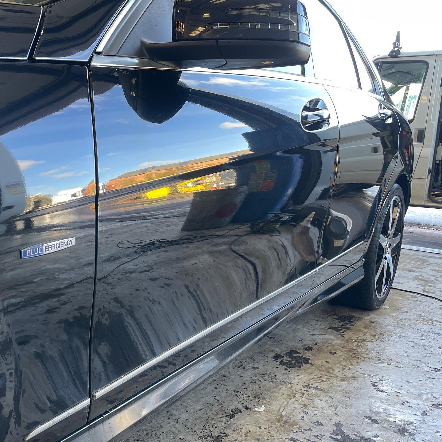 Glossy dark vehicle panel showing a machine polishing finish